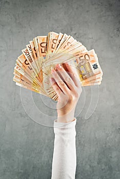 Woman holding fifty euros stack