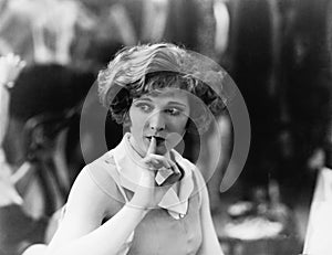 Woman holding a finger in front of her mouth signaling to be quiet