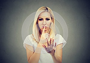 Woman holding finger on lips in calming gesture
