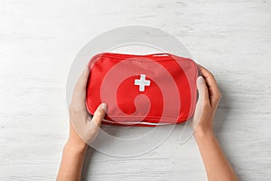 Woman holding first aid kit on wooden background photo