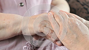 Woman holding flabby wrinkled hands of old woman