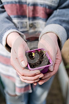 woman holding a flower pot prepared for planting in a greenhouse - gardening and people concept