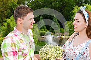 Woman holding flowers while cute man looks at her