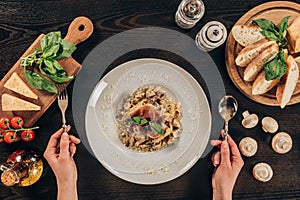 woman holding fork and spoon and going to eat pasta