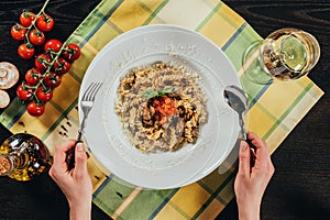 woman holding fork and spoon and going to eat pasta