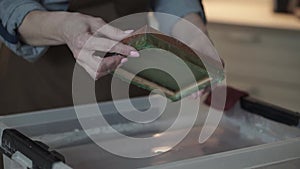 A woman holding a frame for making paper sheets from recycled paper. Selective focus. Household hobby, paper recycling. The concep