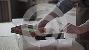 A woman holding a frame for making paper sheets from recycled paper. Selective focus. Household hobby, paper recycling. The concep