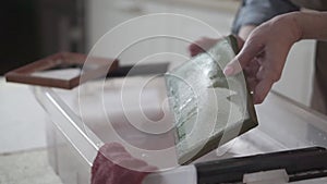 A woman holding a frame for making paper sheets from recycled paper. Selective focus. Household hobby, paper recycling. The concep