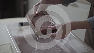 A woman holding a frame for making paper sheets from recycled paper. Selective focus. Household hobby, paper recycling. The concep