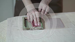 A woman holding a frame for making paper sheets from recycled paper. Selective focus. Household hobby, paper recycling. The concep