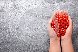 Woman holding fresh goji berries on background, top view. Space for text