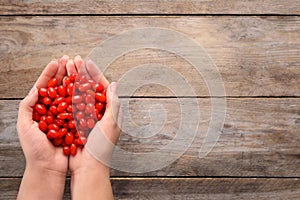 Woman holding fresh goji berries on wooden background. Space for text