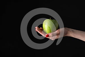 Woman holding fresh ripe green apple against black background, closeup