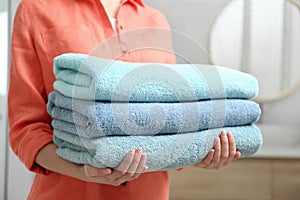 Woman holding fresh towels in bathroom