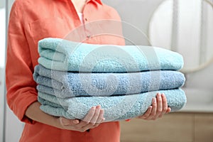 Woman holding fresh towels in bathroom photo