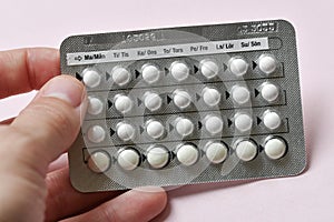 A woman holding full chart of birth control pills