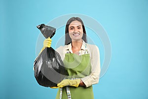 Woman holding full garbage bag on blue background