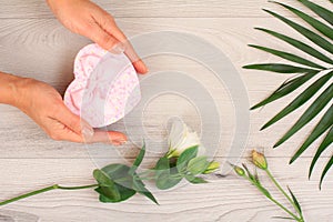 Woman holding a gift box in the hands with flowers on the background