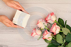 Woman holding a gift box in the hands with flowers on the background