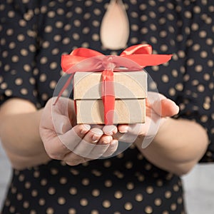 Woman holding a gift box tied with a red ribbon