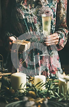 Woman holding glass of champaigne and gift box, Christmas eve