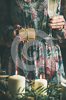 Woman holding glass of champaigne and gift box in hands