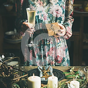 Woman holding glass of champaigne and gift box, square crop