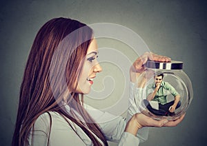 Woman holding a glass jar with imprisoned man in it photo