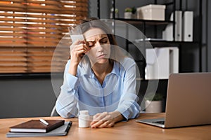 Woman holding glass of medicine for hangover in office