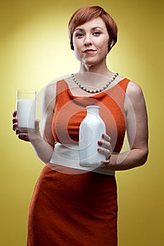 Woman holding glass of milk and bottle