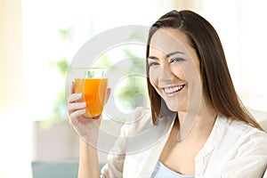 Woman holding a glass of orange juice looking at you