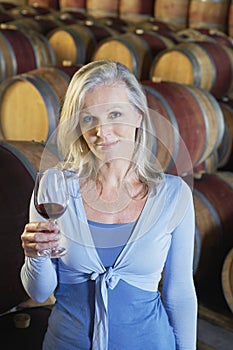 Woman Holding Glass Of Red Wine In Cellar