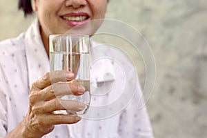 woman holding a glass of water Drinking enough water per day promotes good health.