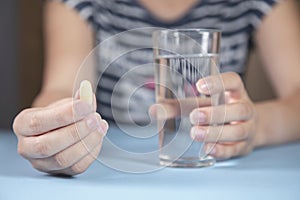 Woman holding glass of water and drug