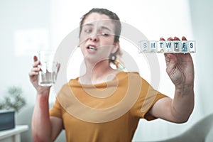 Woman holding glass of water and pills to treat allergy