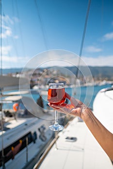 Woman holding glass of wine against yachts at the harbor of Poros. Greece