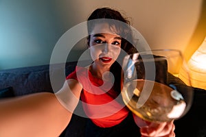 Woman Holding Glass of Wine, Smiling and Making Selfie For Friends or Relatives. Online Cheers and Communication