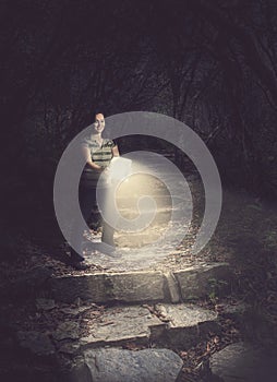 Woman holding a glowing Bible in the forest