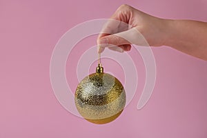 Woman holding golden Christmas ball on pink background, closeup. Space for text