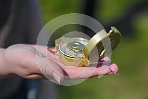 woman holding a golden compass in her hand during the day