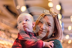 Happy woman holding baby in church on Christmas eve