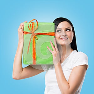 A woman is holding a green gift box. Blue background.