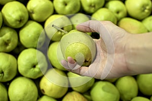 A woman holding a green pear