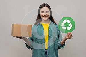 Woman holding green recycling sign and cardboard package, saving environment, ecology concept.