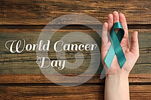 Woman holding green ribbon on background, top view. World Cancer Day