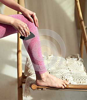 Woman holding the Gua Sha comb with the curved side against her leg. Massaging and relaxing muscles before training, warming up.