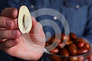 Woman holding half of fresh Ziziphus jujuba fruit, closeup