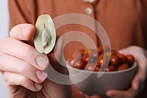 Woman holding half of fresh Ziziphus jujuba fruit, closeup