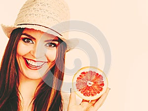 Woman holding half of grapefruit citrus fruit in hand