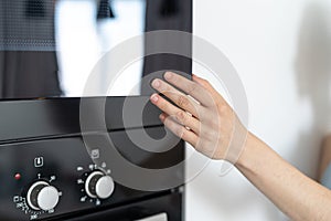 Woman holding hand on black microwave door